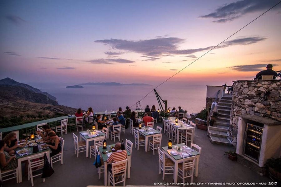 the sunset at 'Manalis Winery' terrace tourists sitting on the tables and enjoy a wine tasting and food